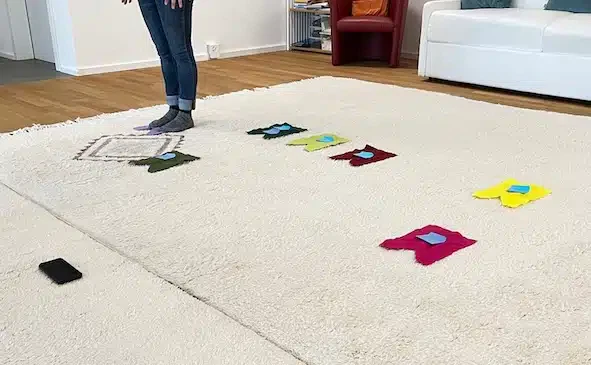 Eine Aufstellung mit Filzchen als Stellvertreter. Man sieht die Füsse einer Person und sieben Filzchen.